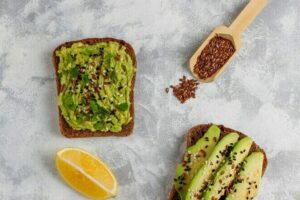 avocado-open-toast-with-avocado-slices-lemon-flax-seeds-sesame-seeds-black-bread-slices-top-view_2831-799